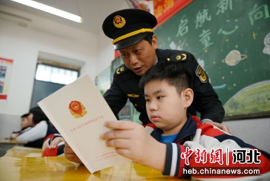 圖為叢臺區(qū)市場監(jiān)督管理局工作人員在指引小學生閱讀食品安全法手冊。 作者 周紹宗